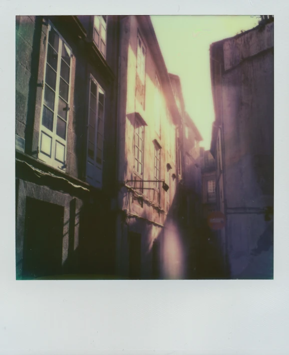 a long narrow alley way with windows, balconies and shutters on either side