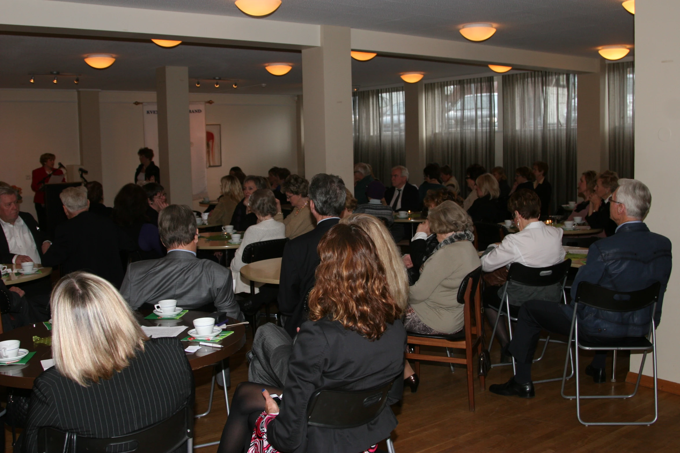 many people sit at tables in a restaurant eating