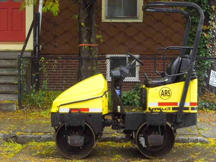 a small yellow vehicle parked in front of a red building