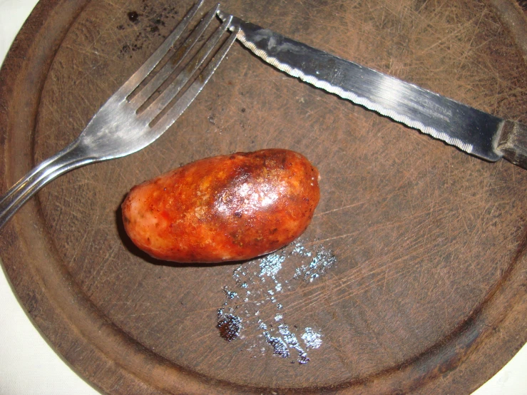 a potato is on a wooden plate next to a knife and fork