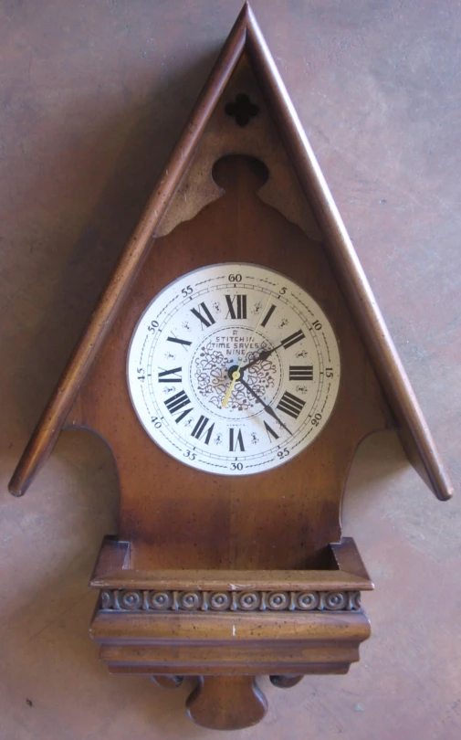 a wooden clock with roman numerals sits on a wall