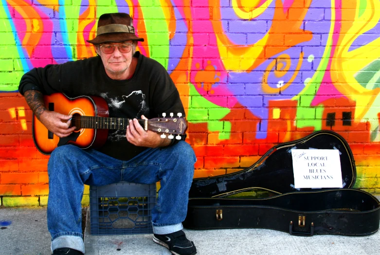 a man is playing the guitar in front of a wall