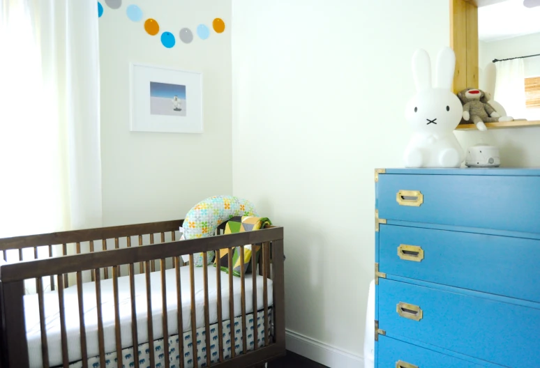 the nursery room has a blue dresser and bed in it