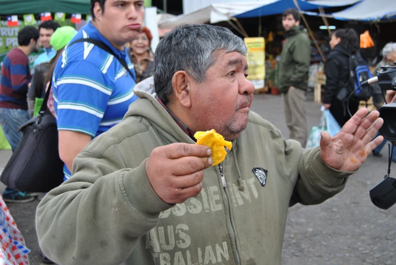 a man holds up a piece of food as he eats it