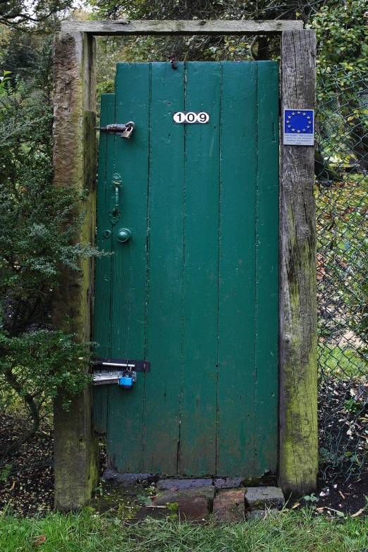 a green door sits on the side of a grassy hill