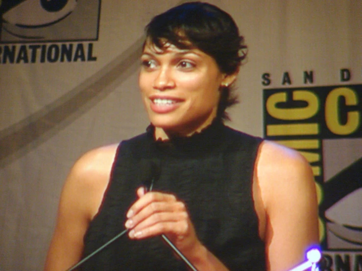 a woman standing at a table in front of a microphone