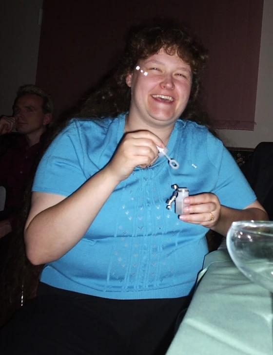 a woman sitting at a table with a drink and a toothbrush