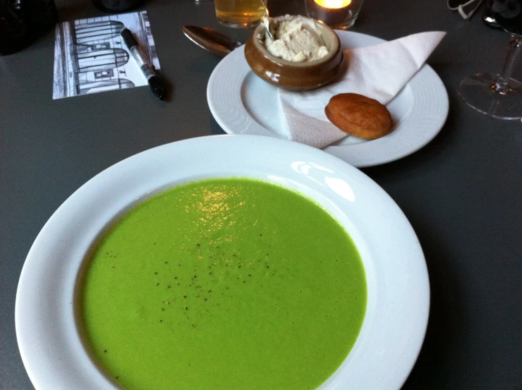 the green soup is served on white plates