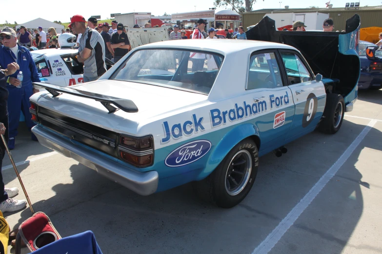 an older blue and white car parked with other older cars