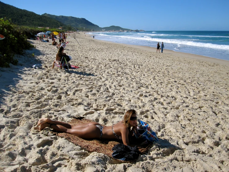 a woman in a bikini laying on a beach