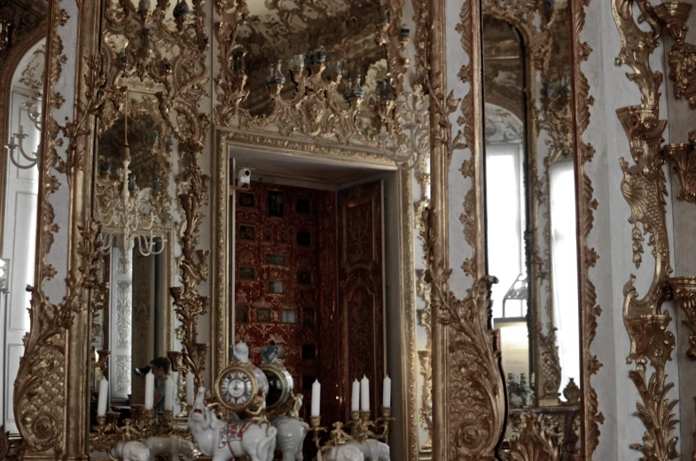 a mirror in an ornately decorated room with several candles and a figurine