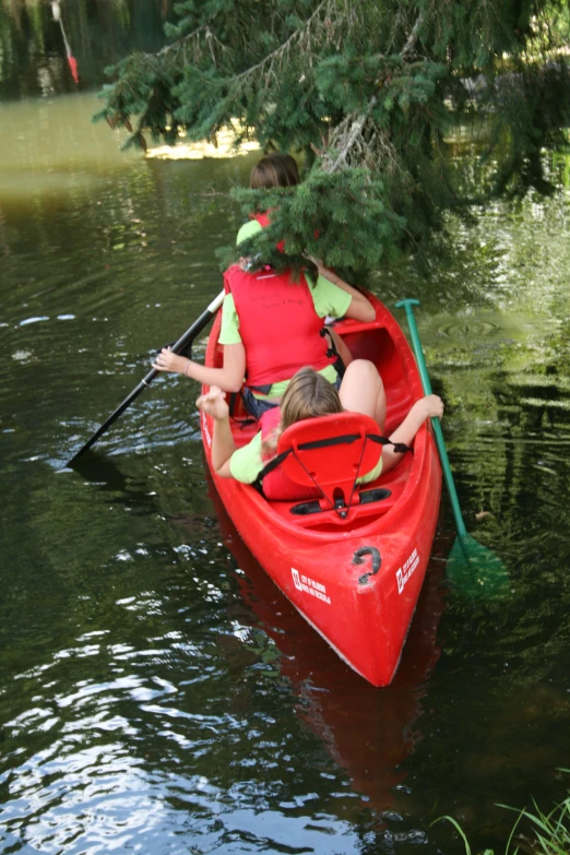 two people in a red canoe with trees reflected on the water