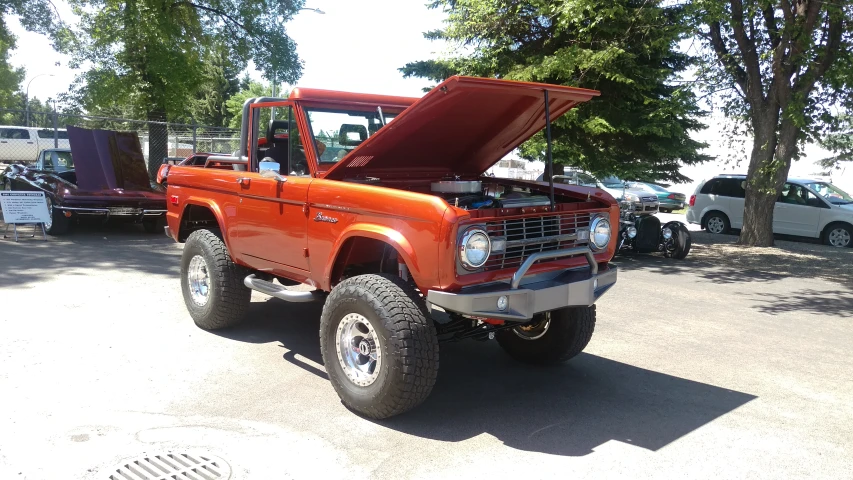 an orange truck with the hood up sitting in a parking lot