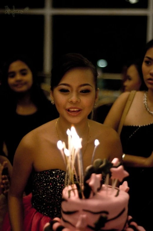 a woman in evening dress getting ready to blow out her birthday cake