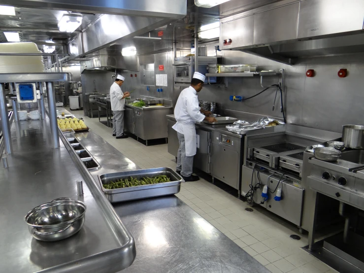 a kitchen filled with metallic equipment and people cooking