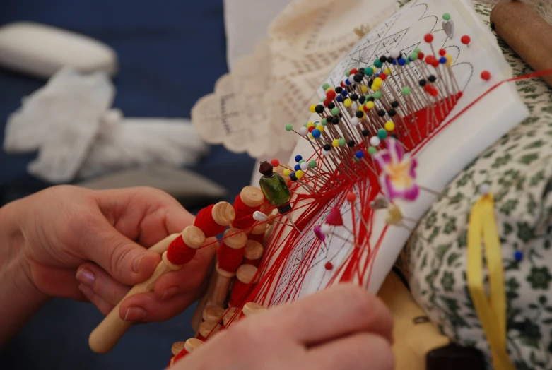 the person is weaving thread onto the loom