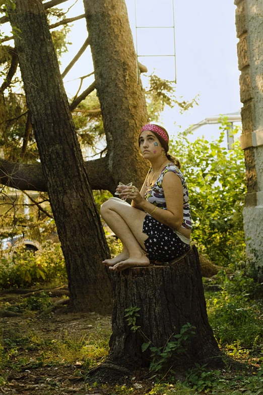 a woman is sitting on top of a tree stump