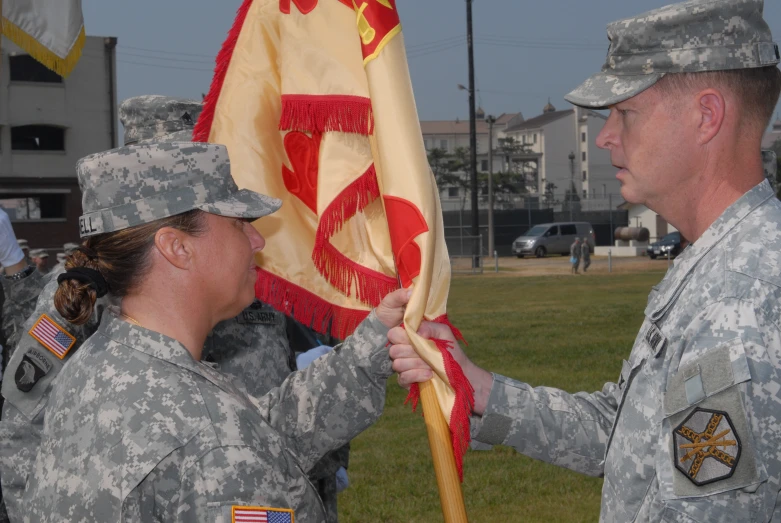 two female soldier standing holding a flag in front of another