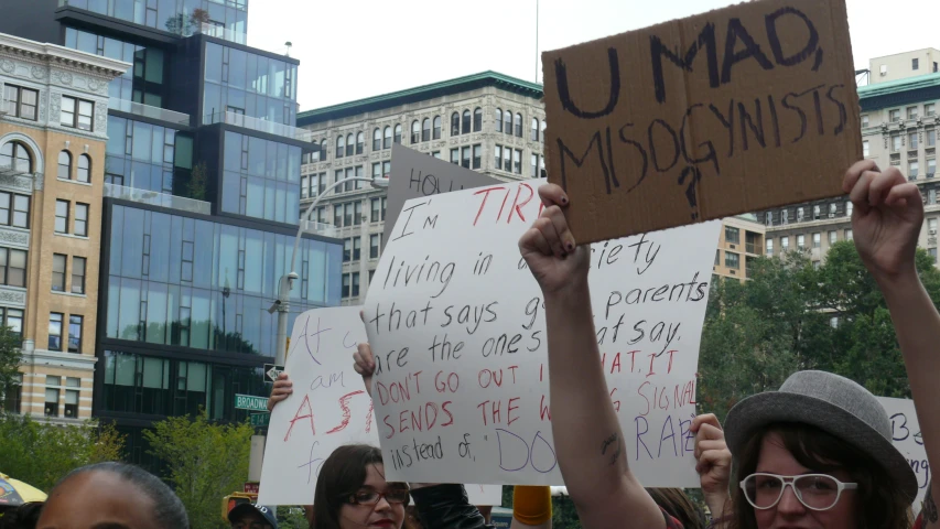 people holding signs and cups in front of a crowd