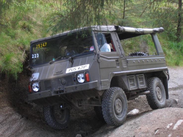 a military vehicle driving down a forest road