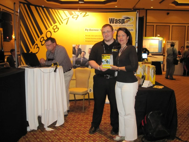 the man and woman are posing with a book in front of a table