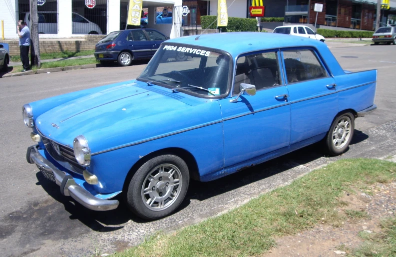 blue antique car parked in front of a white building