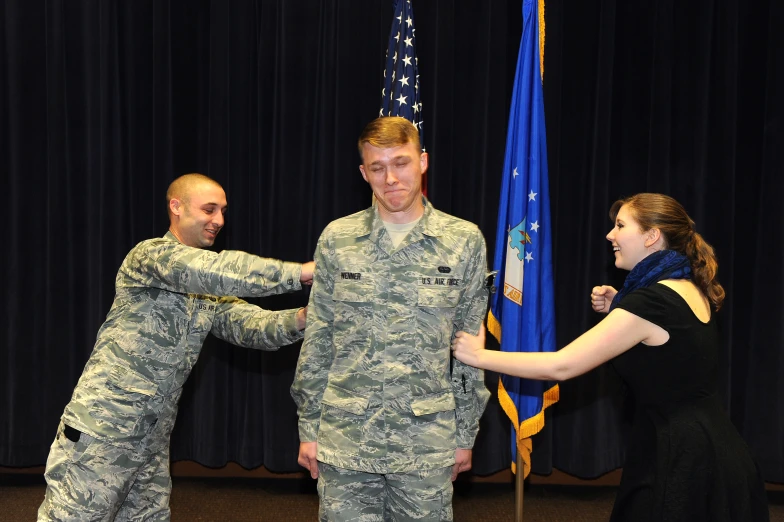 two soldiers greeting each other while standing in front of an american flag