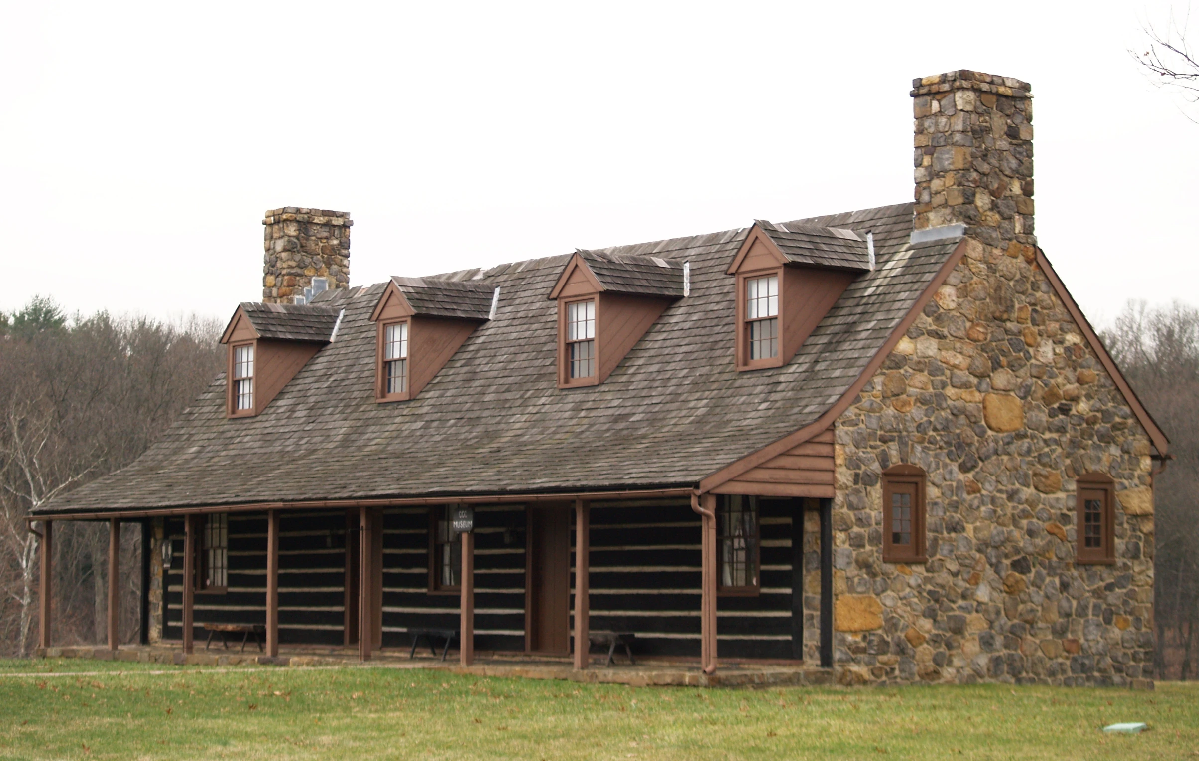 a log cabin with a tall chimney in the grass