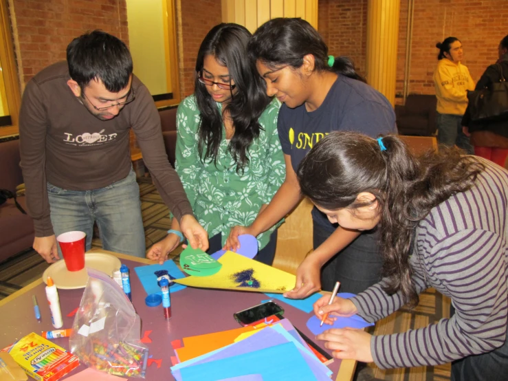 three people at a table with a table top, cardboard blocks and colorful shapes