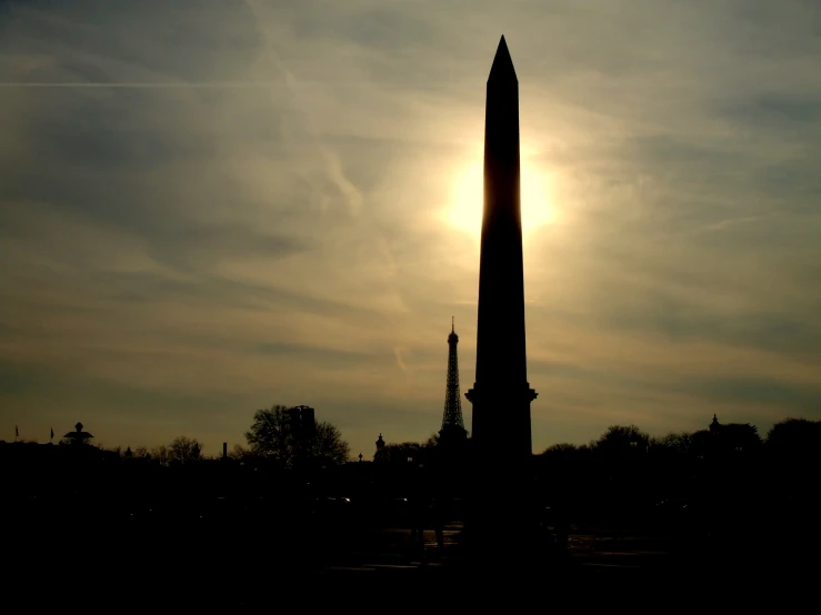 a monument with the sun in the background