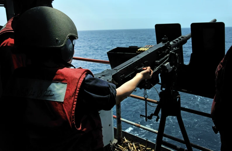 a man shooting a gun at the sea