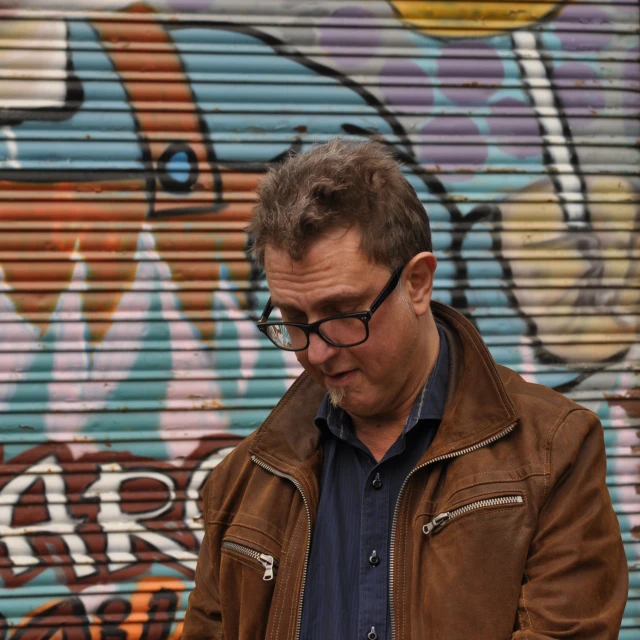 a man is looking at a cellphone while standing in front of a graffiti wall