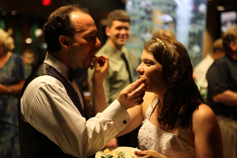 a man feeding a woman cake at an event