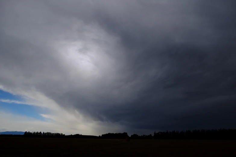 a large field filled with grass under clouds