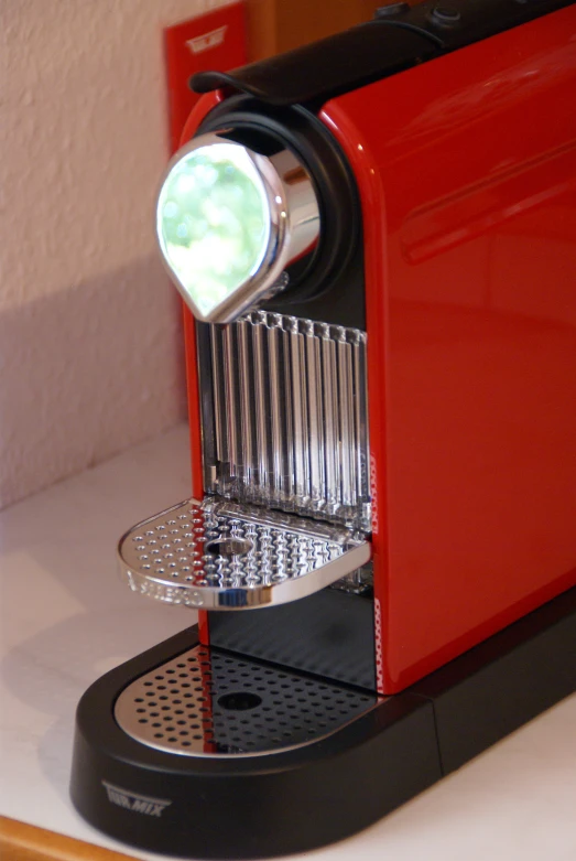 a red toaster on a white counter with a green light in the window
