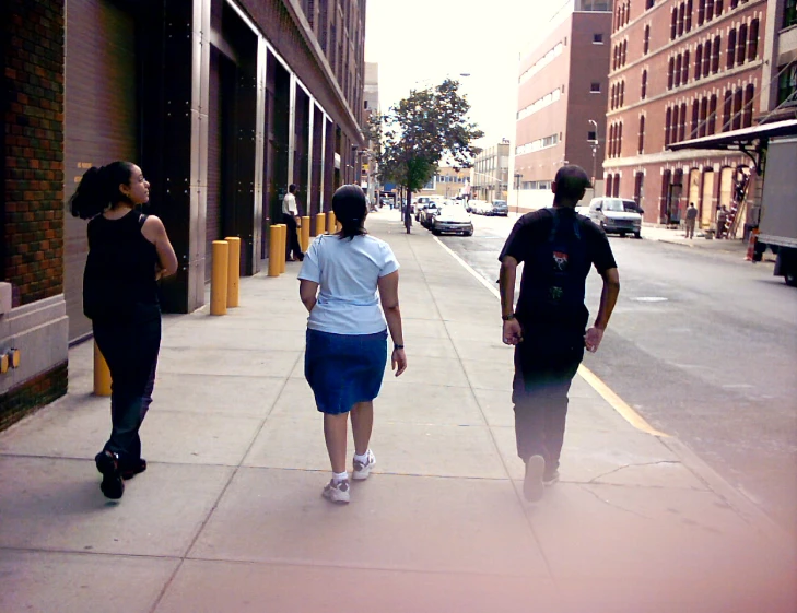 three people walking down the street in a line