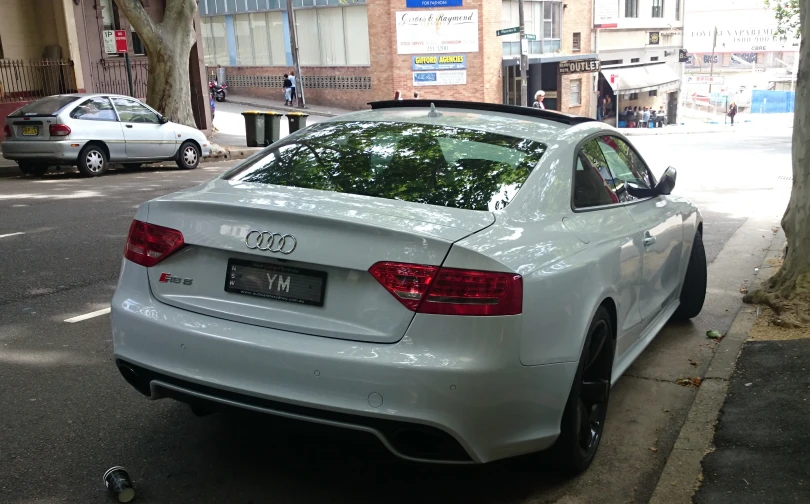 a white car is parked at the side of the street