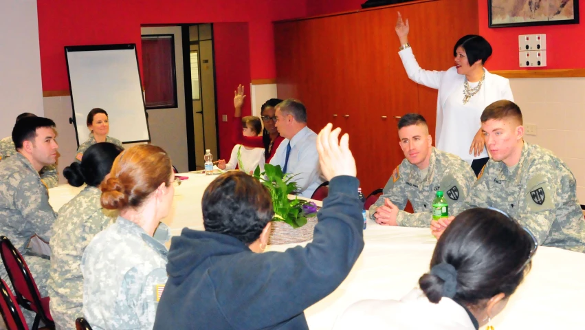 military personnel are around a table and giving a toast to soldiers