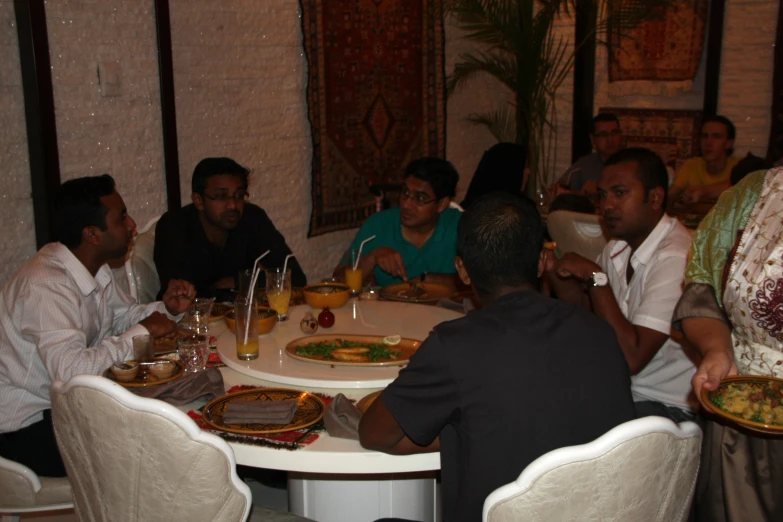 the group of people are sitting around a table with food