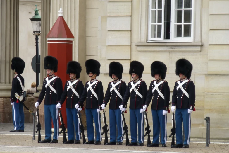 men in uniforms and helmets at attention outside a building