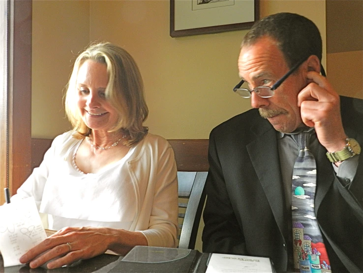 a man and a woman sitting at a table with books