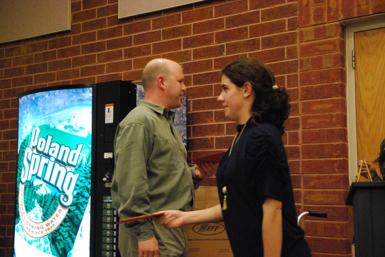 two people are talking to one another in front of a sign