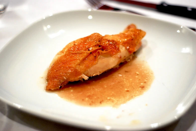 a piece of fish with sauce is sitting on a plate