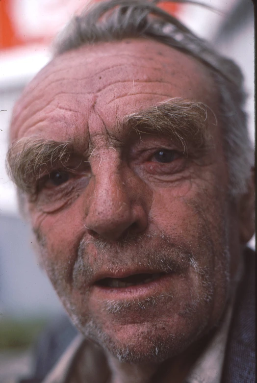 an old man with gray hair and a suit is looking at the camera