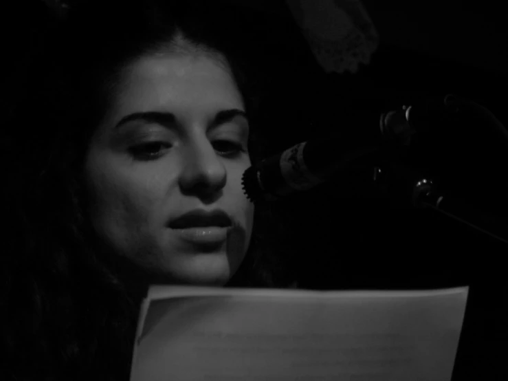 a woman looks at paper while using a microphone