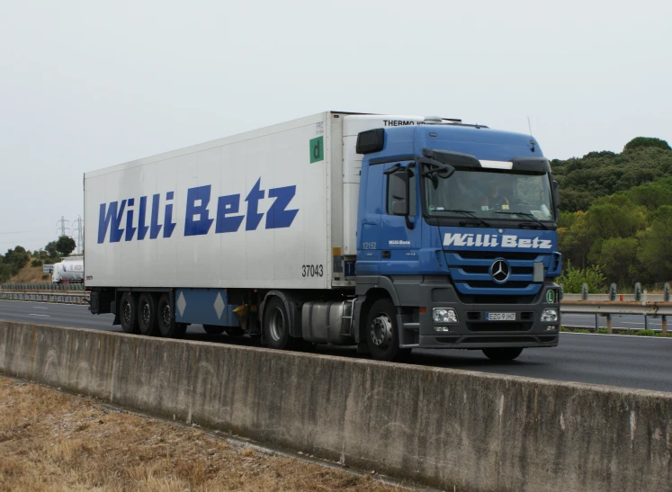 the blue and white truck is driving on the highway