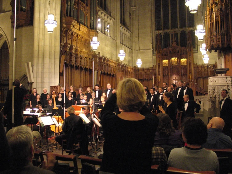 orchestra members in large church with light from large chandelier