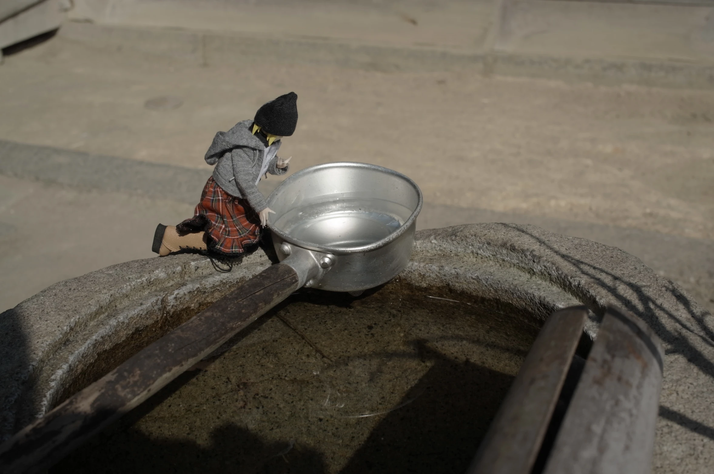 a doll sitting on the edge of a metal container