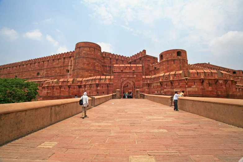 two people walking along a bridge near a large building