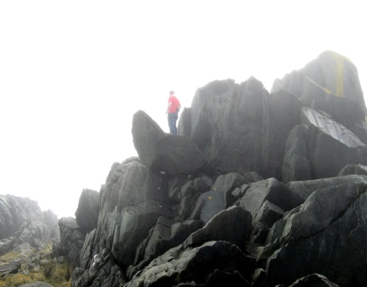 a man is standing on the top of a rocky hill